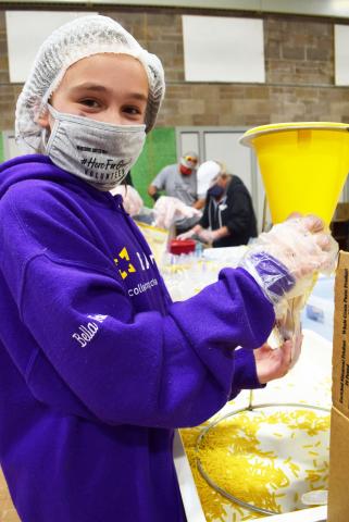 Bella, a student at BART, helps pack meal bags at a volunteer event