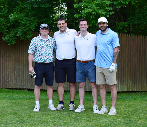 4 men stand on golf green