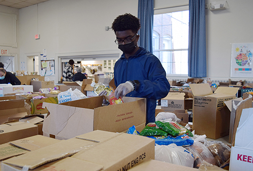 high school student packs a meal box at a pantry