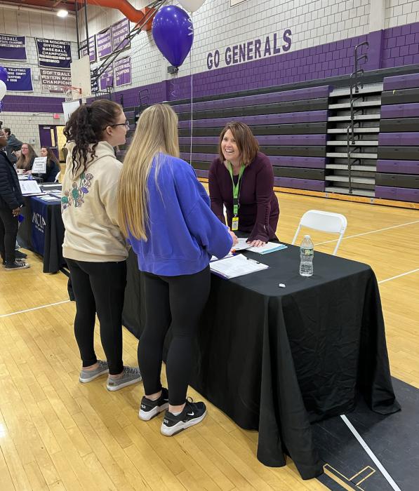 woman talks with students at table