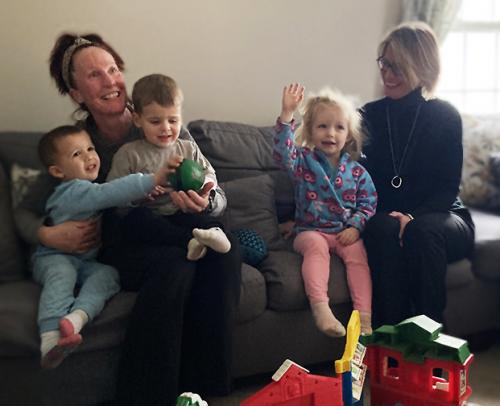 two women and three children sit on a couch