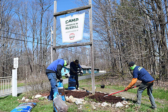 three men mulch a garden bed