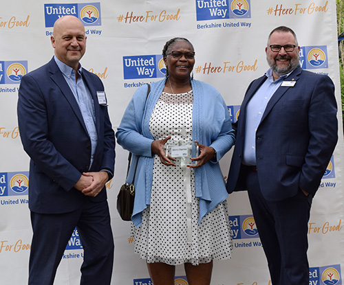 woman holds award standing between two men