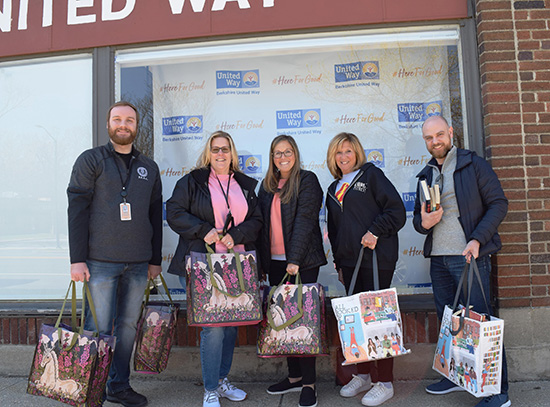 five people hold bags filled with books