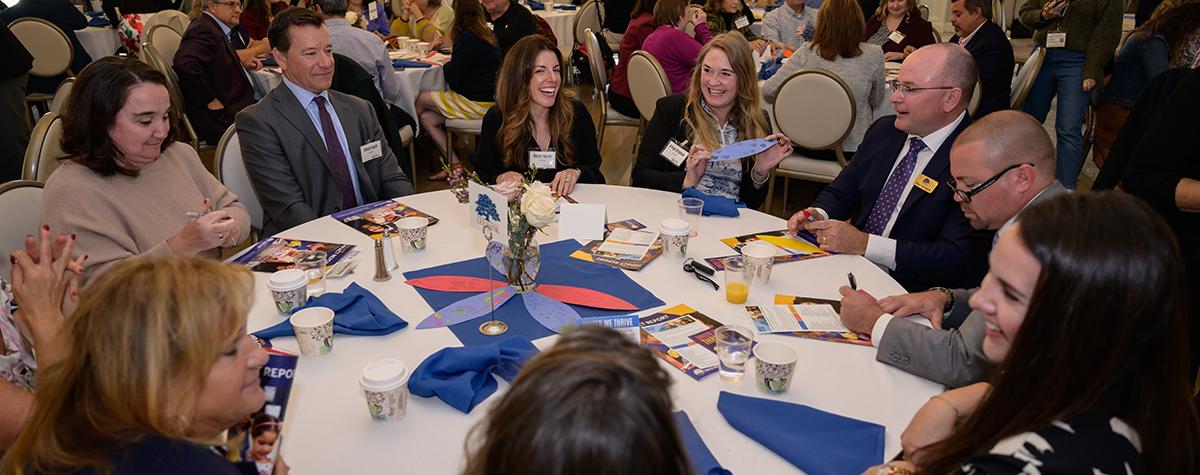 men and women sit at table talking and laughing