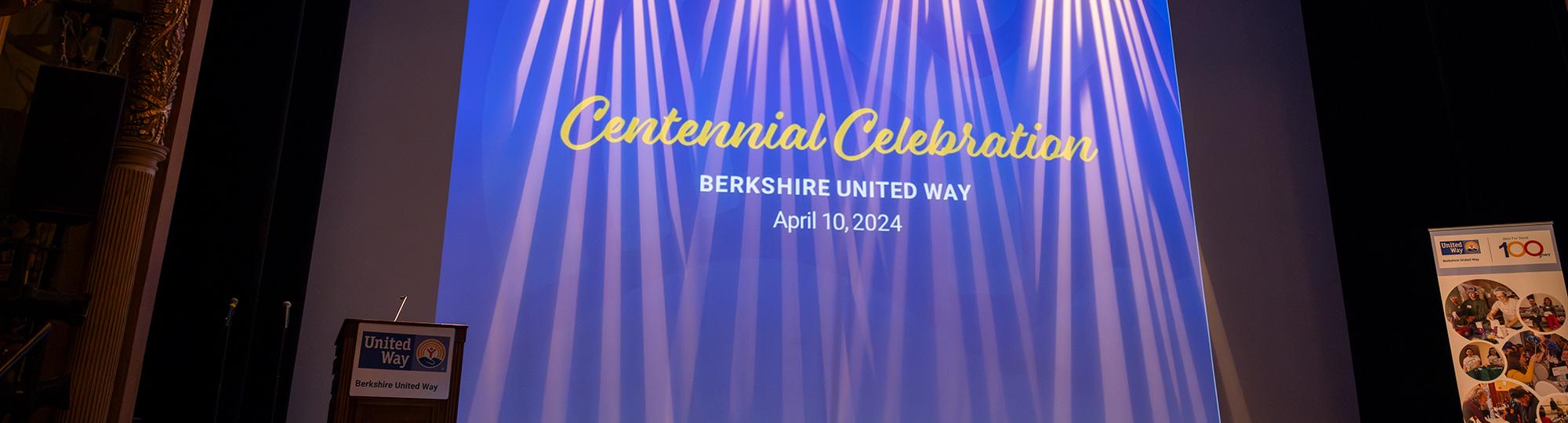 centennial celebration projected on a screen with blue background and lights