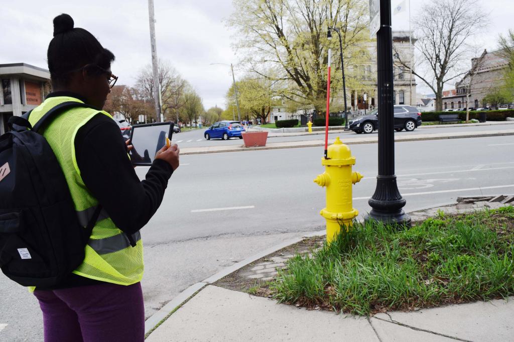 A PHS student snaps a photo of a grassy area along the sidewalk