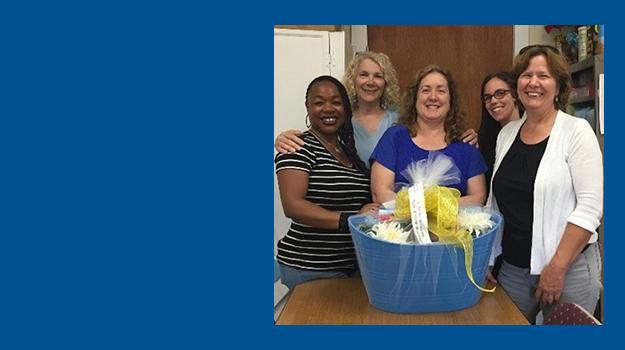 5 women stand with a gift basket