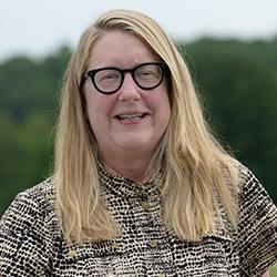 caucasian woman, long blonde hair, glasses, black and white pattern dress