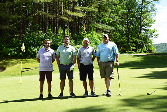 4 men stand on golf green