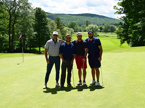 4 men stand on golf green